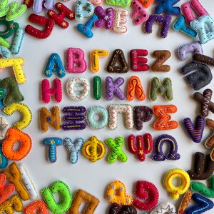 May include: A collection of brightly coloured felt letters, hand-stitched with decorative thread. The letters are arranged to form words, with each letter featuring unique patterns and colours. A creative craft project with an educational focus.