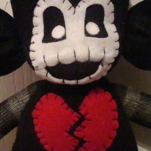May include: Black and white plush toy with a stitched-on face and a large red felt heart with a stitched-on crack down the middle.