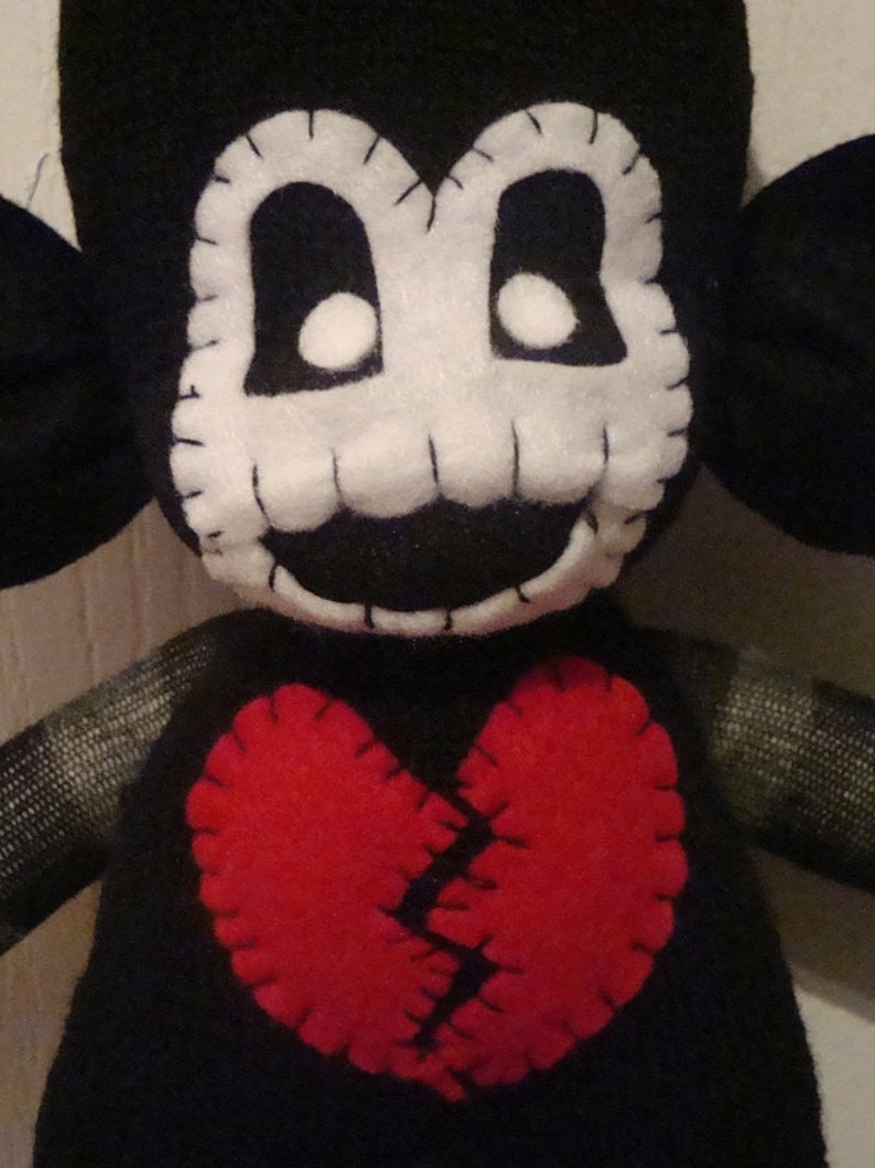 May include: Black and white plush toy with a stitched-on face and a large red felt heart with a stitched-on crack down the middle.