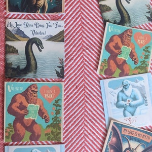 May include: A set of eight Valentine's Day cards featuring various mythical creatures. The cards are printed on a thick cardstock and feature colorful illustrations. The cards include a yeti, a bigfoot, a monster, and a sea serpent. The cards are perfect for sending to friends, family, or loved ones.