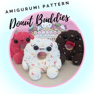 May include: Three crocheted donut amigurumi plushies. One is pink with white sprinkles, one is white with colorful sprinkles, and one is brown with white sprinkles. The donuts have faces and are standing on a white surface.