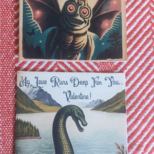 May include: Three vintage Valentine's Day cards featuring illustrated monsters. The first card shows a creature with large wings and glowing red eyes. The second card shows a green sea monster with a long neck. The third card shows a red heart with the text "I have a crush on you".