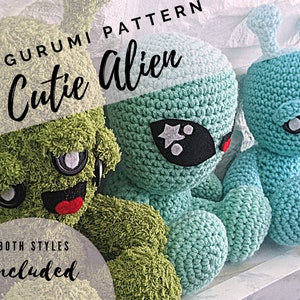 May include: Two crocheted amigurumi alien toys. One is green with a fuzzy texture and the other is light blue. Both have black eyes and red mouths. The text "Cutie Alien" and "Amigurumi Pattern" is written above the toys. The text "Both Styles Included" is written below the toys.