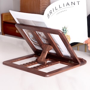 May include: A dark brown wooden book stand with a personalized inscription "Merry Christmas". The stand is holding a magazine titled "Brilliant Journal".