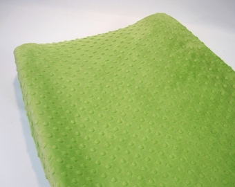 May include: A close-up of a bright green fabric with a textured, dotted pattern. The fabric is soft and plush, perfect for crafting projects or making baby blankets.
