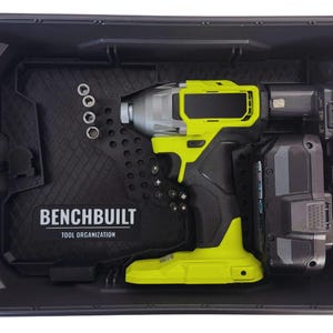 May include: A black plastic tool case containing a lime green and black cordless impact driver, two battery packs, and a black organizer insert with the text BENCHBUILT TOOL ORGANIZATION printed in white, featuring slots for small metal bits.