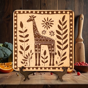 May include: A brown cork trivet with a decorative design of a giraffe, flowers, and leaves. The trivet is on a wooden stand.