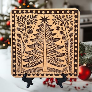Peut inclure: Un dessous de plat en liège avec une bordure noire et un motif brun et noir d'un sapin de Noël stylisé avec une étoile au sommet. Le dessous de plat est sur une surface blanche avec des baies rouges et une boule de Noël rouge en arrière-plan.