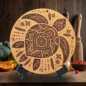 May include: A round cork trivet featuring a decorative design of a turtle with intricate patterns. The turtle is brown and the background is a light brown cork.