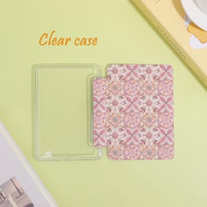 K&ouml;nnte beinhalten: Eine transparente Handyh&uuml;lle mit einem gemusterten Einsatz. Der Einsatz hat ein sich wiederholendes Blumenmuster in Rosa, Rot und Grau. Die Worte "Clear case" sind in Orange geschrieben.