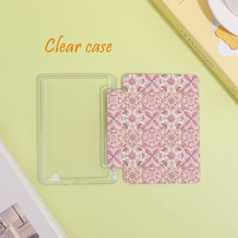 K&ouml;nnte beinhalten: Eine transparente Handyh&uuml;lle mit einem gemusterten Einsatz. Der Einsatz hat ein sich wiederholendes Blumenmuster in Rosa, Rot und Grau. Die Worte "Clear case" sind in Orange geschrieben.