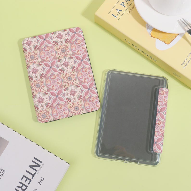 K&ouml;nnte beinhalten: Eine offene und eine geschlossene E-Reader-H&uuml;lle mit einem rosa-wei&szlig;en Blumenmuster. Die offene H&uuml;lle ist transparent mit einem schwarzen Bildschirm. Die geschlossene H&uuml;lle hat ein passendes Blumenmuster. Der Hintergrund ist hellgr&uuml;n.