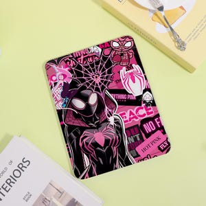 May include: A rectangular tablet case featuring a vibrant pink and black graphic design. The artwork displays a stylised character in a black suit with pink spider web patterns, alongside various stickers including a spider logo and the text HOT PINK.