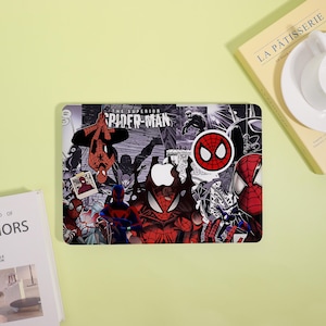May include: A laptop skin featuring a collage of Spider-Man comic book art in red, black, and white. The design includes the text The Superior Spider-Man, various character poses, a circular mask icon, and a cutout for the central Apple logo.