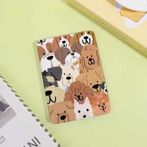 Peut inclure: Une coque de téléphone rectangulaire ornée d'un motif de chiens de différentes races, aux couleurs variées. Les chiens sont représentés avec des traits de dessins animés, dans des tons de marron, de blanc et de noir. Fond vert clair.