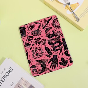 May include: A rectangular tablet case featuring a vibrant pink background with a repeating black line art pattern of mystical symbols including a snake, a crescent moon, a hand, an hourglass, crystals, a cat, mushrooms, and a book labeled Spells.