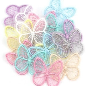 May include: A selection of embroidered butterfly appliques in pastel shades. The butterflies have delicate, openwork wings and are arranged in a scattered pattern. Colours include pink, blue, yellow, and lavender.