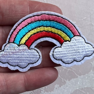 Può includere: Toppa arcobaleno ricamata con archi rosa, blu, gialli e rossi. L'arcobaleno è bordato di nero e ha nuvole bianche a ciascuna estremità. La toppa è progettata per essere cucita o stirata sul tessuto.