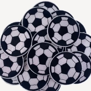 Könnte beinhalten: Eine Ansammlung runder, gestickter Aufnäher mit einem Fußball-Design. Jeder Aufnäher hat ein schwarz-weißes Farbschema, wobei das Fußballmuster deutlich sichtbar ist. Die Aufnäher sind in einem Haufen angeordnet, wobei sich einige überlappen.