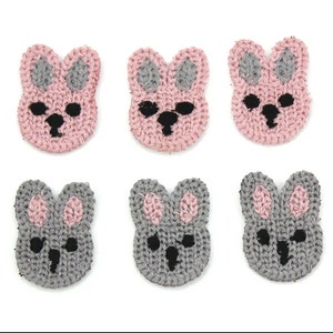 May include: Six handmade crochet bunny face appliques. Three are pink with grey ears, and three are grey with pink ears. Each bunny face has black eyes and a nose. Ideal for crafting projects.