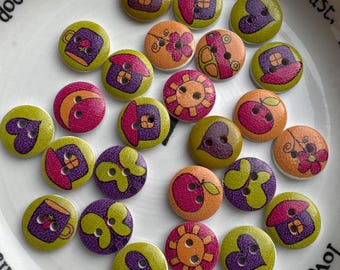 May include: A selection of decorative wooden buttons with diverse designs, such as houses, hearts, flowers, and suns. The buttons display a mix of colours including green, purple, orange, and pink. The buttons are round and have two holes for sewing.