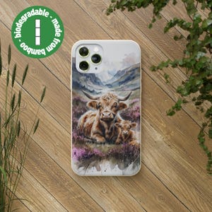 Puede incluir: Una funda de teléfono blanca con un diseño de acuarela de dos vacas de las Tierras Altas en un campo de flores moradas. La funda está hecha de bambú y es biodegradable.