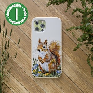 Op de afbeelding: Een witte telefoonhoes met een illustratie van een rode eekhoorn. De eekhoorn staat in een veld met bloemen. De hoes is gemaakt van bamboe en is biologisch afbreekbaar. De tekst "bamboo - made from bamboo - biodegradable" is op de hoes gedrukt.