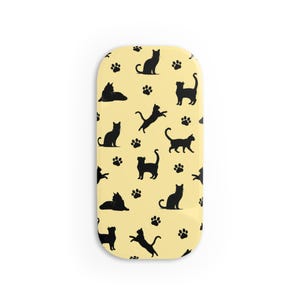 May include: A yellow oval-shaped phone case with a repeating pattern of black cat silhouettes and paw prints.