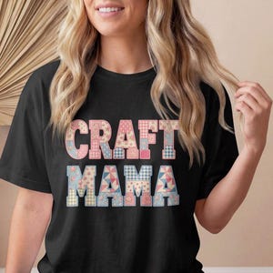May include: A black short-sleeved t-shirt featuring the text CRAFT MAMA in large block letters. The letters are filled with a patchwork pattern of various floral, gingham, and geometric prints in shades of pink, blue, and white.