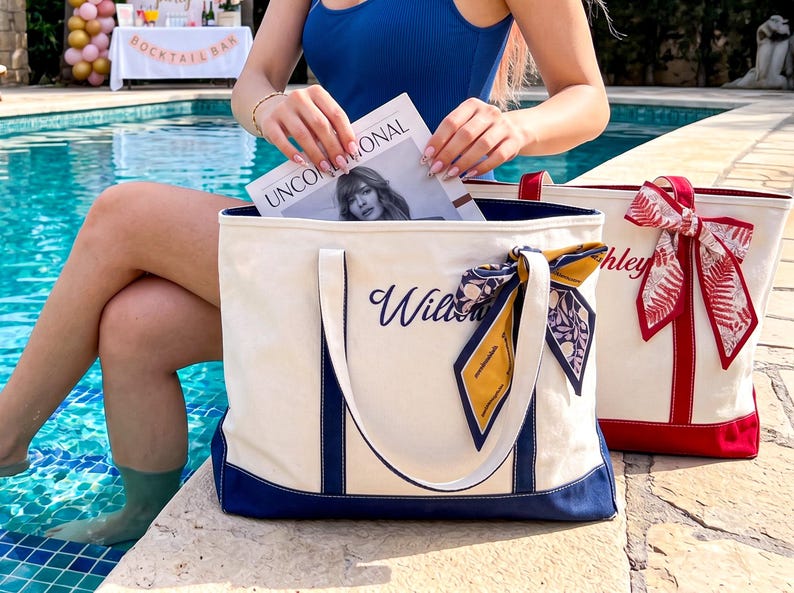 May include: Two canvas tote bags with sturdy handles and reinforced bottoms. The front bag is cream with navy blue trim and a navy blue script name, accented by a patterned silk scarf. The back bag is cream with red trim and a red script name.