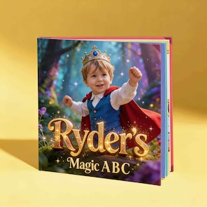 May include: A hardcover children's book with a glossy cover featuring a young child wearing a gold crown and a red cape over a blue vest and white shirt. The title text reads Ryder's Magic ABC in large, gold, glittery, three-dimensional letters.