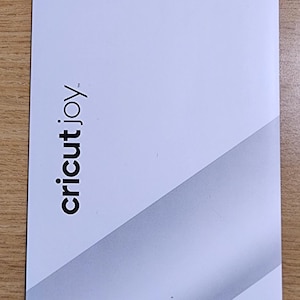 May include: White Smart Label pack for Cricut Joy, featuring writable and removable vinyl. The package includes 4 sheets, measuring 5.5 inches by 13 inches (14 cm x 33 cm). The Cricut Joy logo is at the bottom.