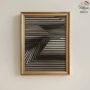 May include: A framed black and white abstract art print. The artwork features a geometric design of parallel lines creating a three-dimensional effect. The frame is gold-colored, and the print is from Palaria Store Prints.