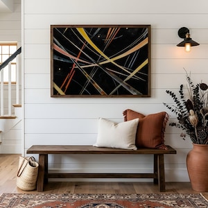 May include: An abstract artwork with a dark backdrop and intersecting lines in yellow, orange, and white hangs above a wooden bench. The bench has cushions and a large terracotta vase with dried plants. A woven basket and rug complete the entryway decor.