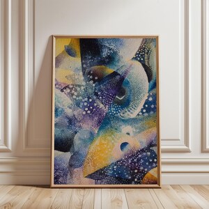 May include: Abstract watercolour painting in a wooden frame. The artwork features a blend of blue, yellow, and purple hues with white dotted patterns. The composition has a dynamic, flowing quality, suggesting movement and depth. The framed art is leaning against a white wall.