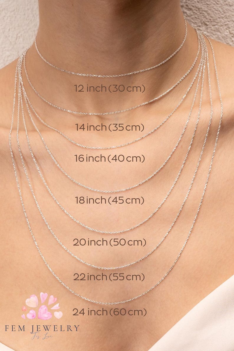 May include: A close-up of a model wearing seven different silver chain necklaces, each with a different length. The lengths are labeled in inches and centimeters, ranging from 12 inches (30 cm) to 24 inches (60 cm).