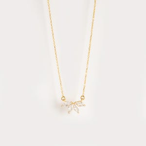 May include: A gold chain necklace with a delicate pendant featuring a cluster of clear marquise-shaped stones.