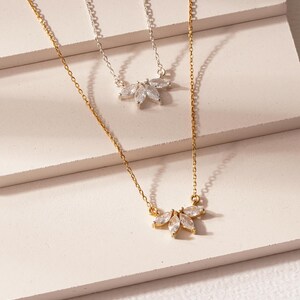 May include: Two delicate necklaces with a cluster of marquise-shaped clear stones in a flower-like design. One necklace is gold and the other is silver.