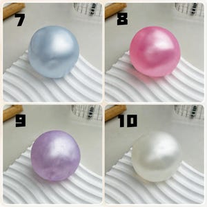 May include: A set of four spherical objects labeled 7 through 10. Number 7 is a metallic light blue sphere, 8 is a metallic pink sphere, 9 is a metallic purple sphere, and 10 is a metallic white sphere. Each sphere has a smooth, glossy finish.