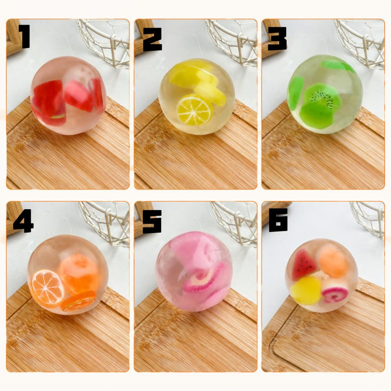 May include: Six clear, spherical stress balls labeled one through six, each containing miniature fruit-shaped inserts. The balls feature red, yellow, green, orange, pink, and multi-colored fruit designs suspended within a transparent, gel-like material.