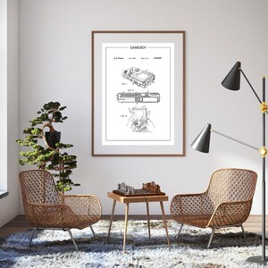 Peut inclure: Un dessin de brevet en noir et blanc d'une console de jeu vidéo portable Game Boy. Le dessin montre la console sous différents angles et comprend du texte décrivant les caractéristiques de l'appareil. Le texte comprend le titre "GAMEBOY" et le numéro de brevet.