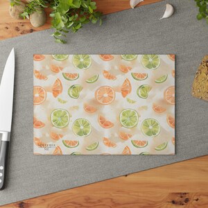 Könnte beinhalten: Ein weißes Schneidebrett mit einem Aquarellmuster aus Orangen- und Limettenscheiben. Der Text "Soulfree Me" ist unten links aufgedruckt.