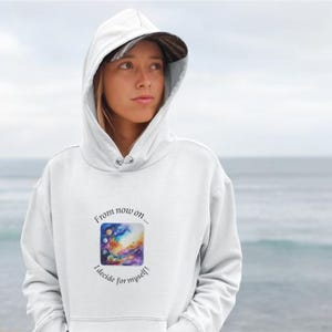 Könnte beinhalten: Weißer Kapuzenpullover mit Kordelzug und einem farbenfrohen quadratischen Grafik auf der Vorderseite. Die Grafik zeigt ein Aquarelldesign mit dem Text "From now on... I decide for myself!"