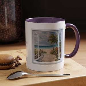 Könnte beinhalten: Weiße Keramik-Kaffeetasse mit lilafarbenen Rand und Henkel. Die Tasse zeigt ein gedrucktes Bild eines Fensters mit Blick auf eine Strandszene mit einer Palme und einem Holzsteg.