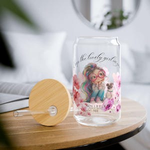 Könnte beinhalten: Eine Glasdose mit Bambusdeckel und Strohhalm. Die Dose hat eine bunte Illustration eines Mädchens mit einem Hund und Blumen. Der Text auf der Dose lautet "Keep the lively girl in you. Soulfree, love me"