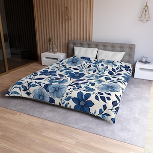 Könnte beinhalten: Ein weißer Bettbezug mit einem blauen Blumenmuster. Der Bettbezug zeigt große blaue Blumen und Blätter auf weißem Hintergrund.