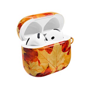 Könnte beinhalten: Weiße kabellose Ohrhörer in einem offenen Etui mit einem Herbstblatt-Design. Das Etui hat ein Muster aus gelben, orangefarbenen und roten Blättern. Die Ohrhörer sind weiß mit schwarzen Details.