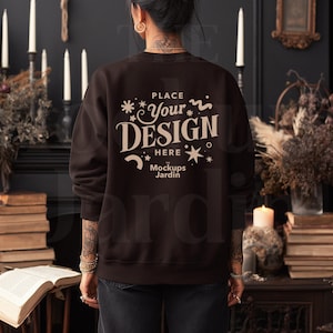 May include: A dark brown sweatshirt with the text "PLACE YOUR DESIGN HERE Mockups Jardin" in a cream color. The sweatshirt is a crew neck style. The image is a mockup, perfect for showcasing designs.