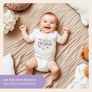 May include: A white baby onesie with short sleeves and a brown print that says "PLACE Your DESIGN HERE Mockups Jardin". The onesie is on a light brown blanket with a white flower and a stuffed animal.