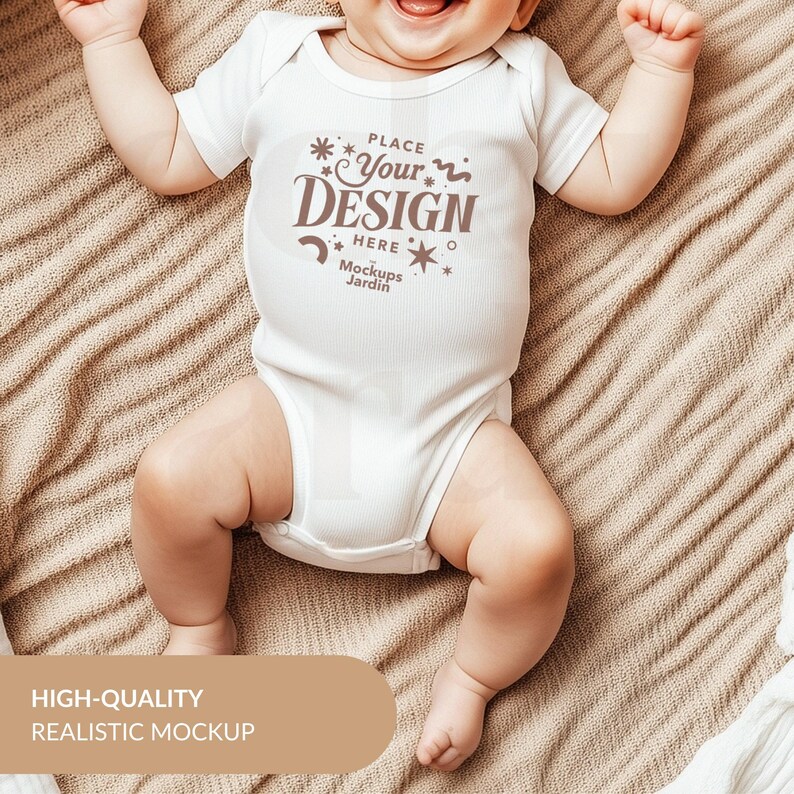 May include: White baby bodysuit with short sleeves and a mock-up design that says "Place Your Design Here" with stars and a wavy line. The text "Mockups Jardin" is below the design.
